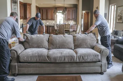 Movers carrying a sofa through a living room