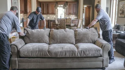 Two Mount Si Movers movers carrying a sofa through a living room